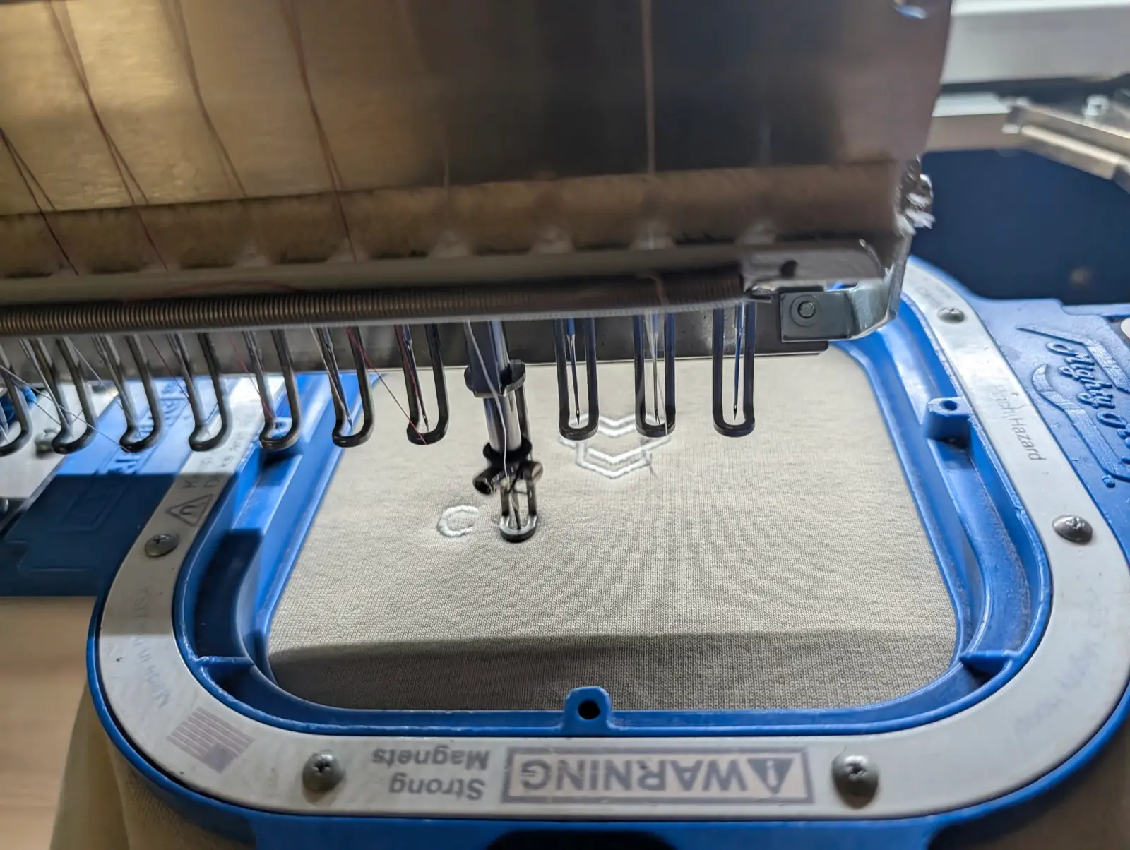 Stickmaschine stickt ein Logo in eingespannten Stoff